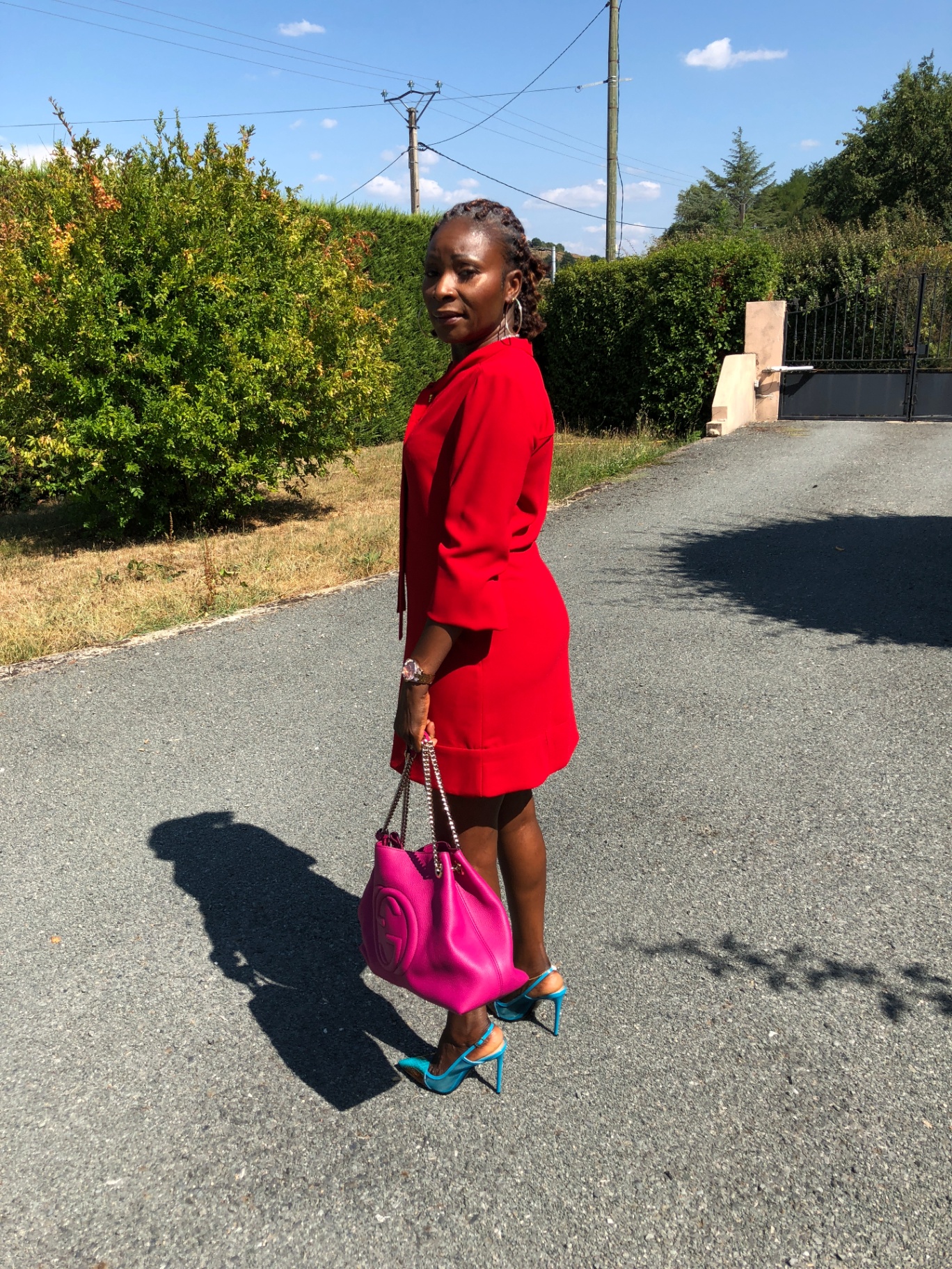 Edwige CBK en look glamour météo Soleil — robe rouge écarlate, sac fuchsia et escarpins turquoise, conseil vestimentaire couleurs vives Reflet Solaire